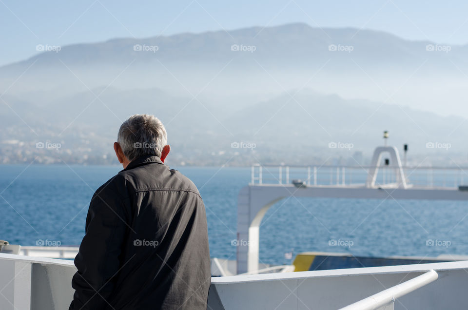 A man is watching the fog while he arrives his destination somewhere in Greece.