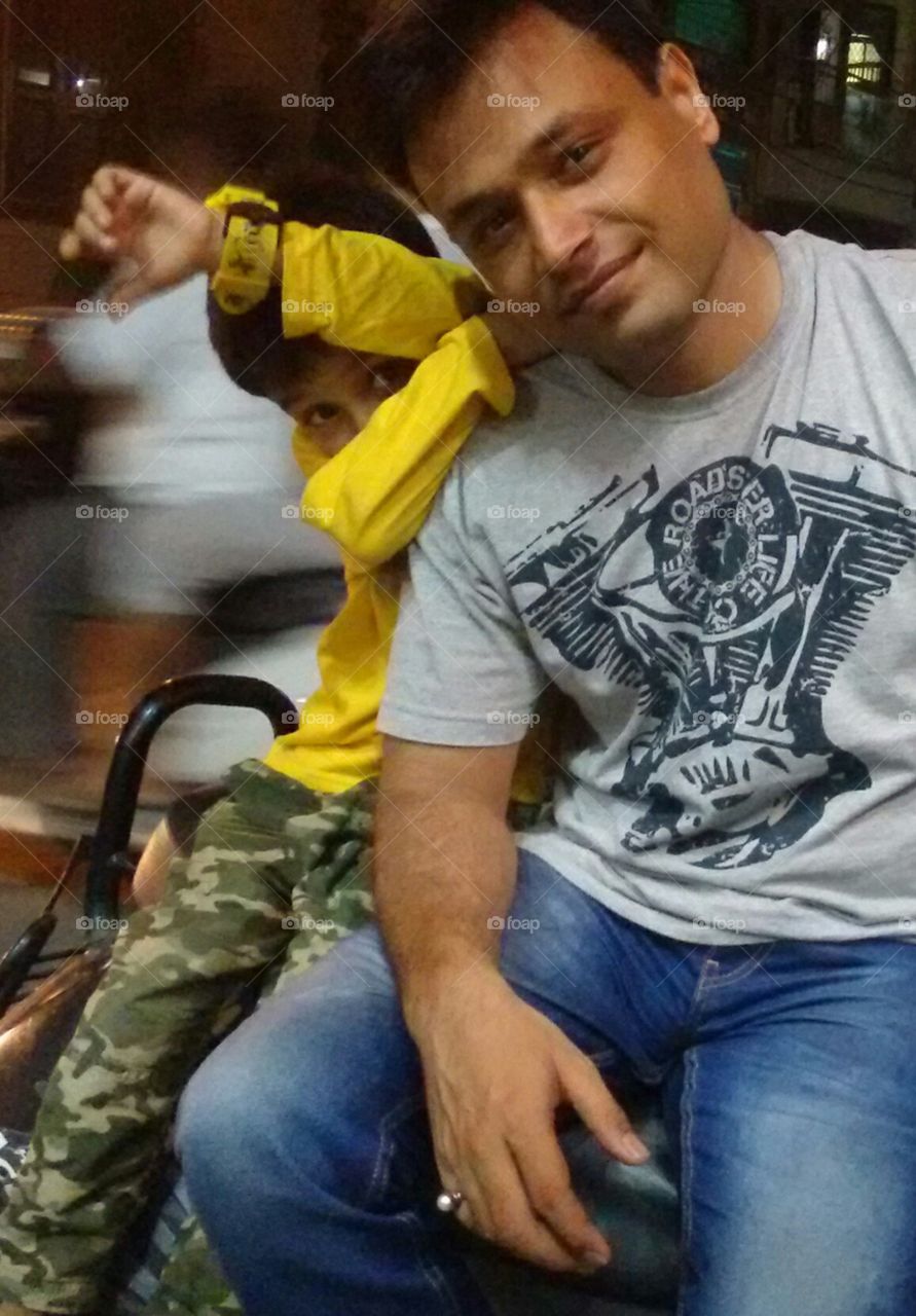A kid is sitting on a two-wheeler with his father