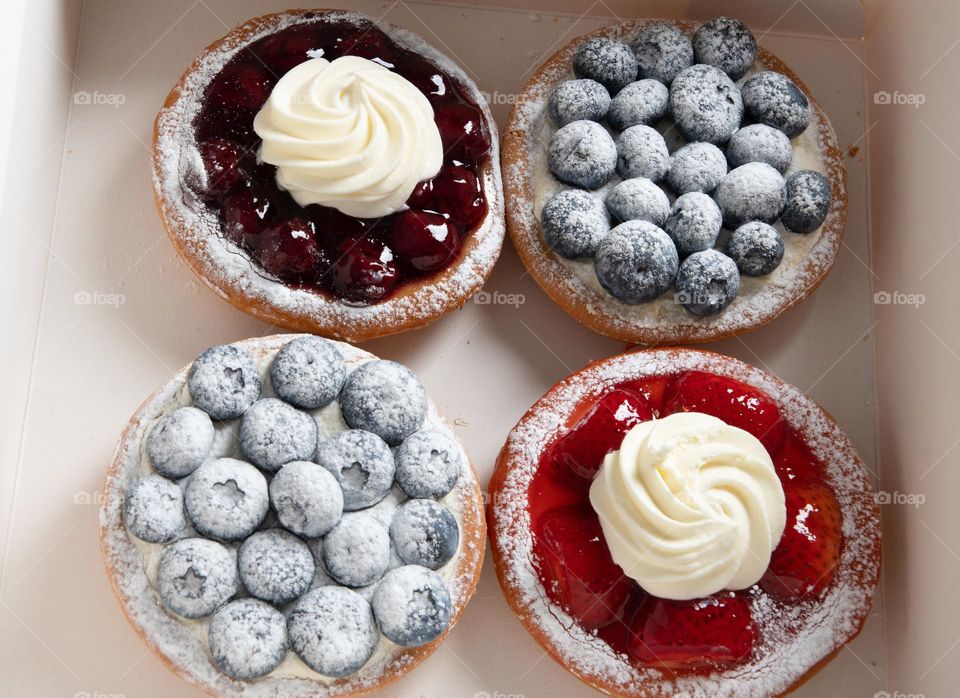a variety of cakes in a box, food delivery to your home, a cake with blueberries and strawberries sprinkled with powdered sugar, decorated with cream, homemade cakes, ordering food online, close-up food photo from above