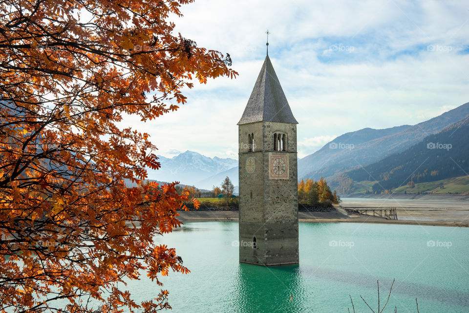 bell tower of a church appears from water, lake Reschen in Italy