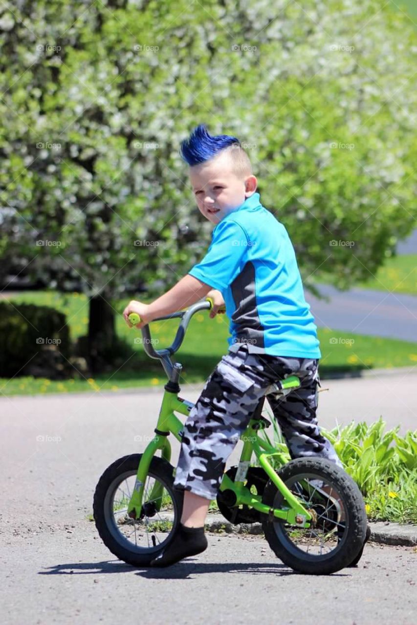 My little boy with a fresh blue mohawk riding his bike on a beautiful summer afternoon. 