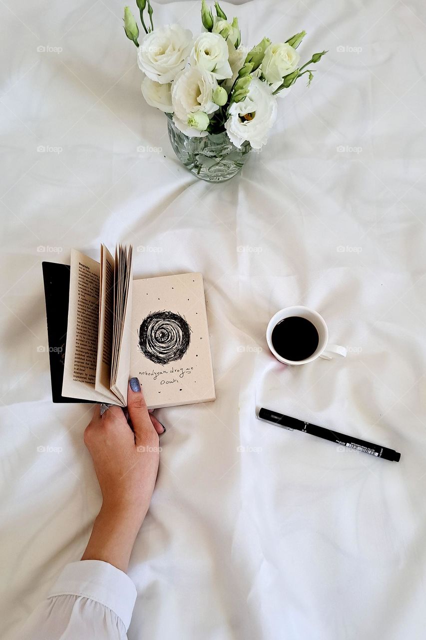 A bouquet of flowers with a cup of coffee and a painting