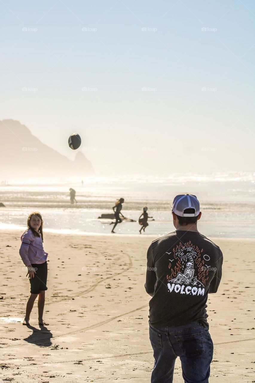 Father and daughter playing catch on the beach 