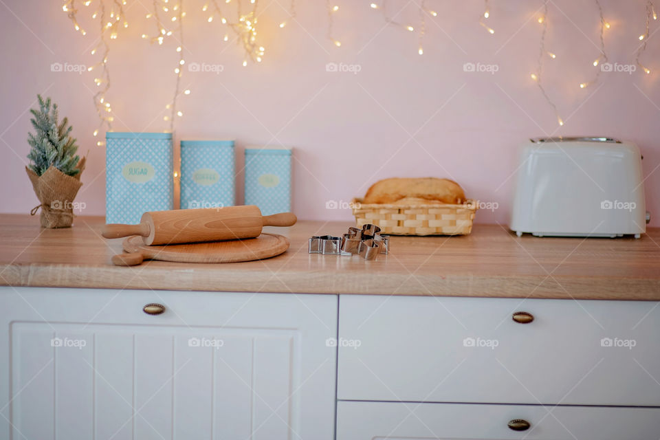 Festive winter cozy kitchen interior with garlands, decorations and gifts.  Christmas dinner at the decorated table.