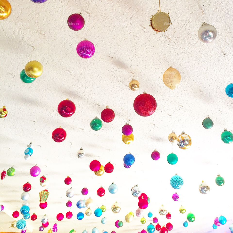 Brightly colored round holiday ornaments hanging from the ceiling 
