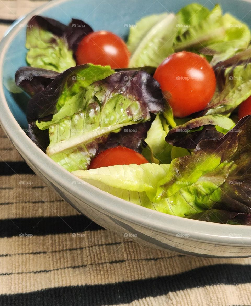 Enjoy the simplicity of a salad bowl with leafy green lettuce and fresh tomatoes off the vine for a healthy meal at home