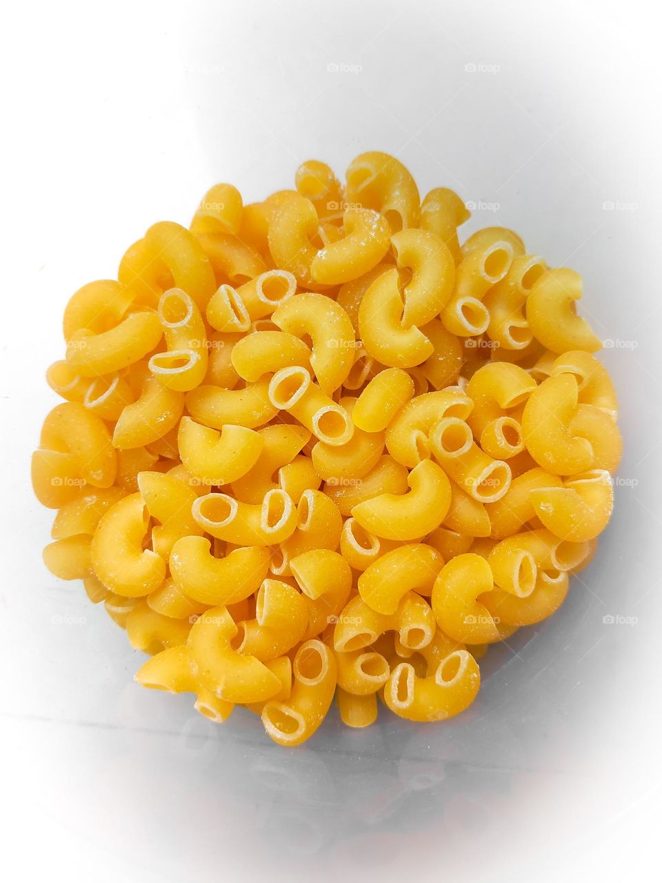 raw macaroni pasta isolated on white background with clipping path and full depth of field. Top view.