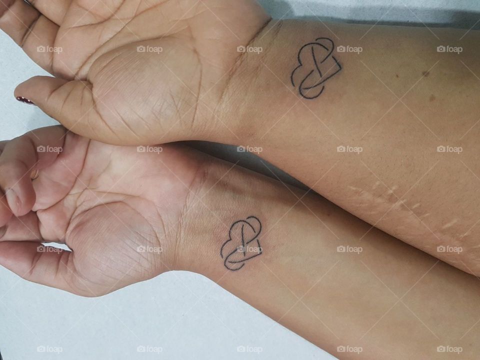 Tatuagem de coração e o símbolo do infinito, representando amizade infinita.