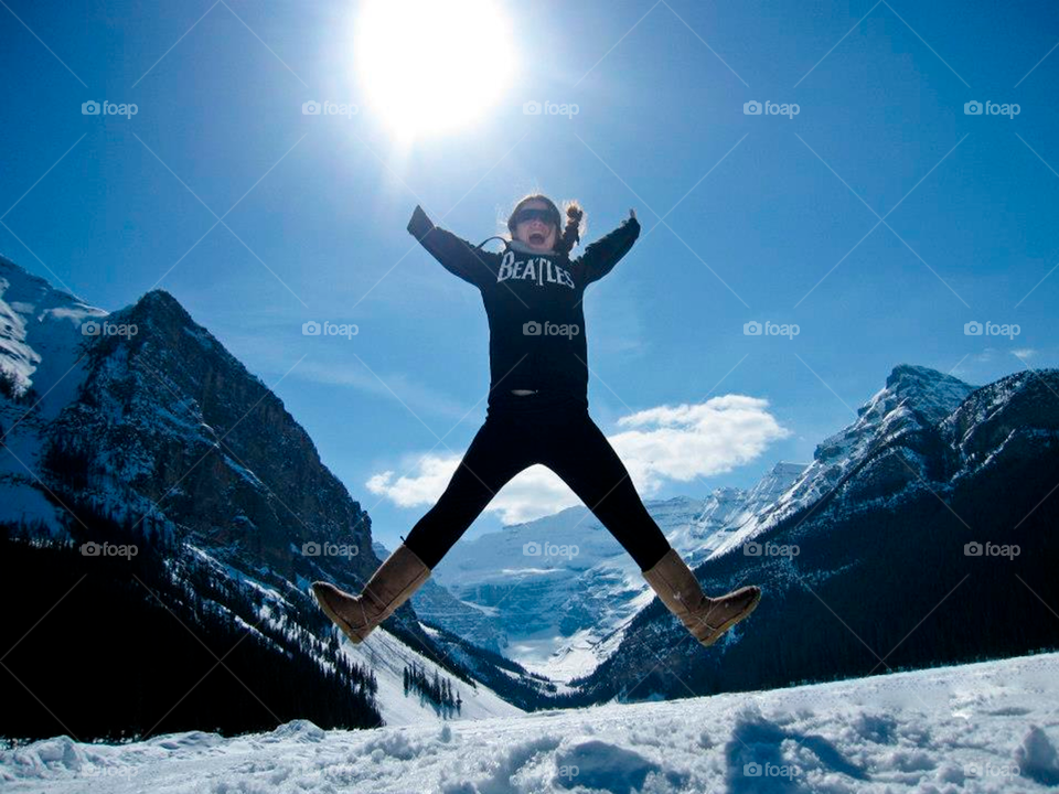 Happy girl jumping with a snowy mountain background