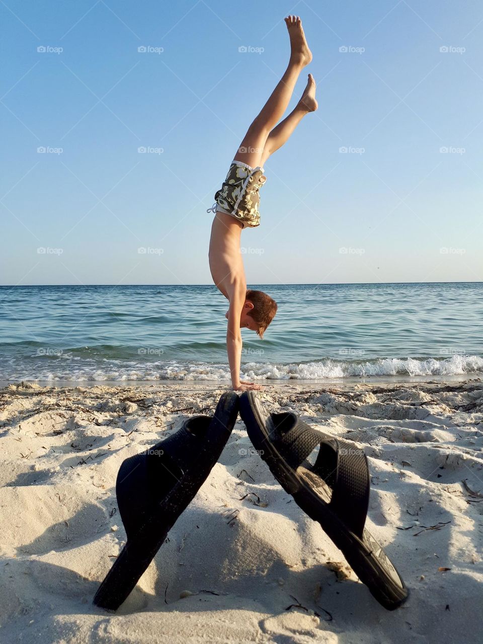 Boy doing hand stand on the beach 