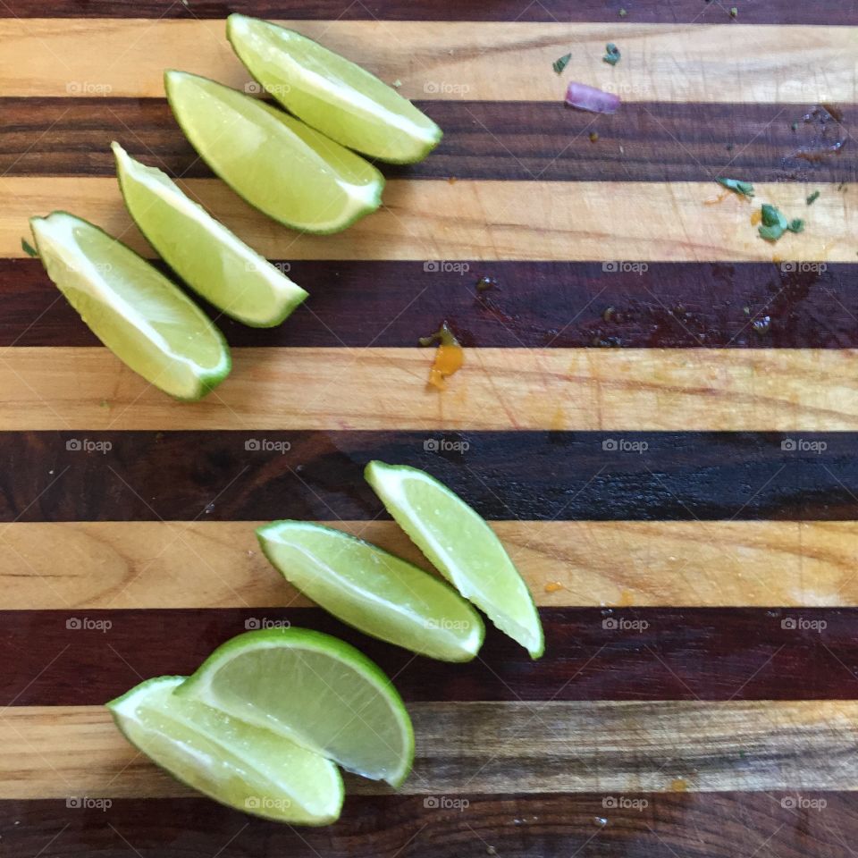 Fresh cut limes on a hand made cutting board. Bit of mango and cilantro residue visible. 
