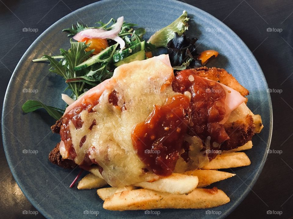 Chicken Parmigiana with chips, ham and salad.