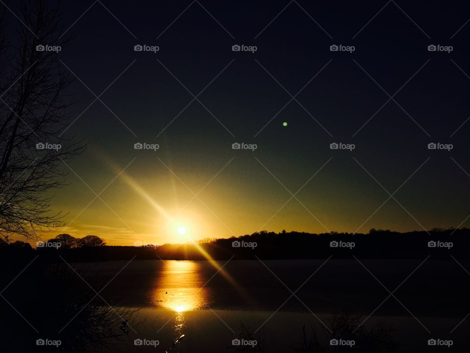 Sun set on iced lake with star reflection tree 