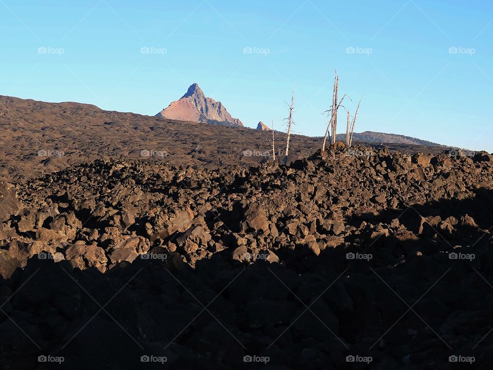 A vast lava rock field leads to the jagged peak of Mt. Washington in Oregon’s Cascade Mountain Range on a sunny fall morning with clear blue skies. 