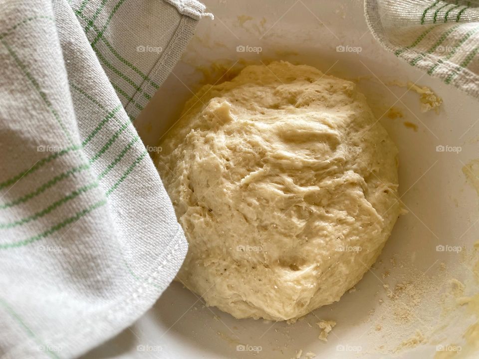 Close-up of yeast dough in a bowl covered with kitchen towel