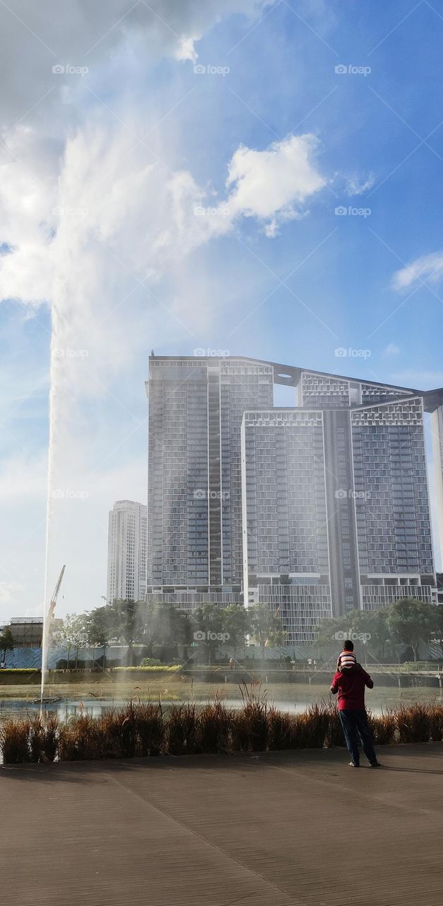 The child ride on his father's shoulder to view the lake and garden.