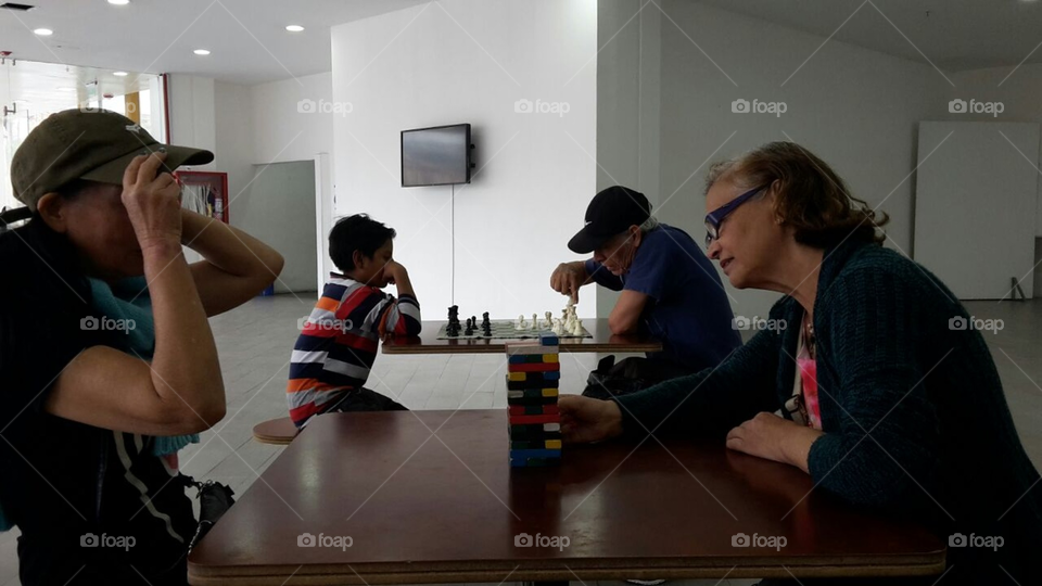 four people and children all of ages playing jenga and chess board games