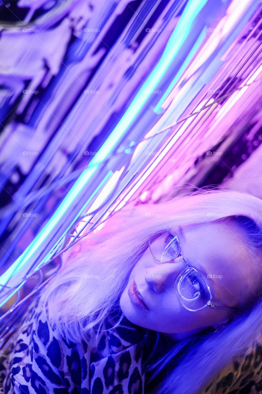 Woman face with glasses in metal frame reflect neon light, selective focus