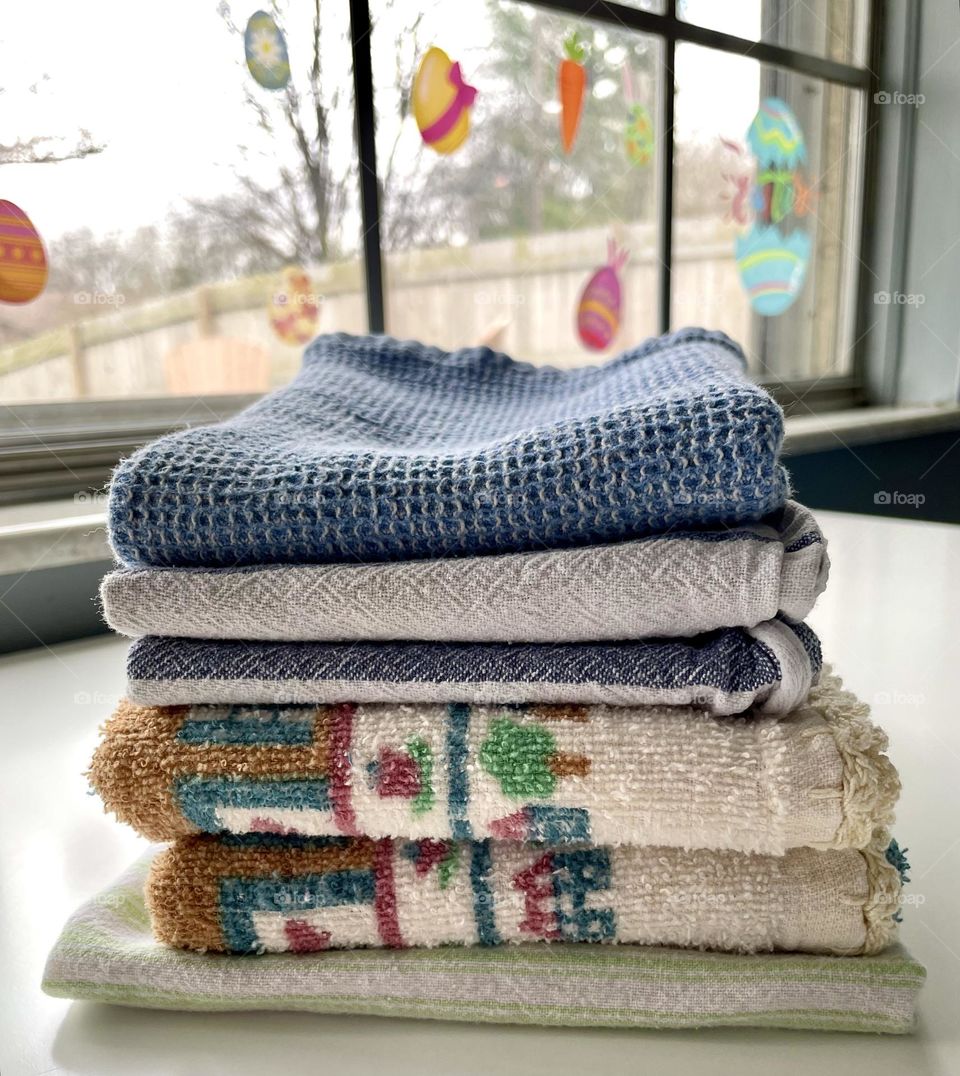 Folding laundry on the kitchen table, daily tasks of life, stack of kitchen towels on table 