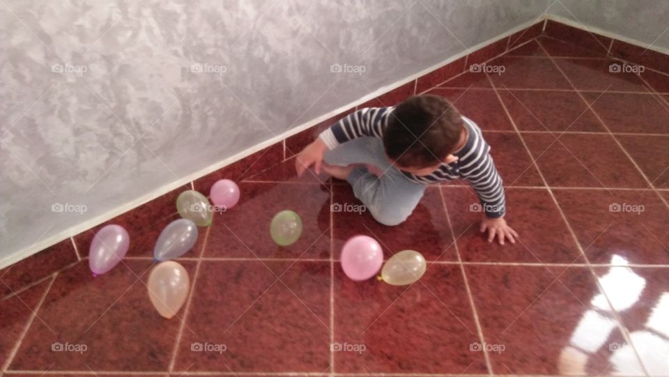 young boy feeling happy when he plays with balloons.