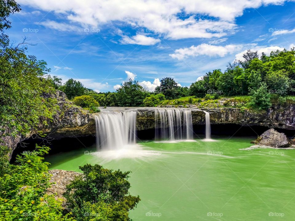 Long exposure photo of waterfall and river pool under blue sky at Zarečki krov in Croatia