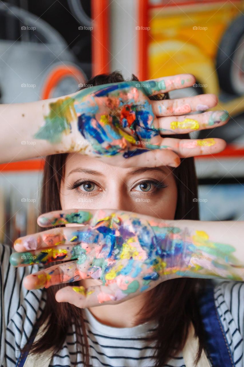 girl artist in her workshop with paint hands