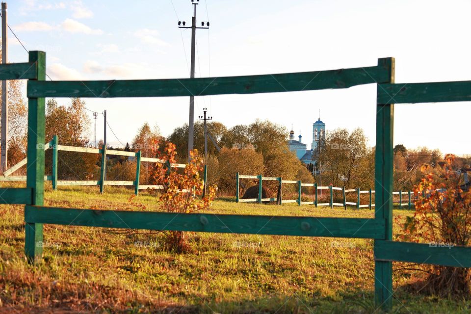 my village in autumn, view of the mown dry grass in the yard and the church in the distance