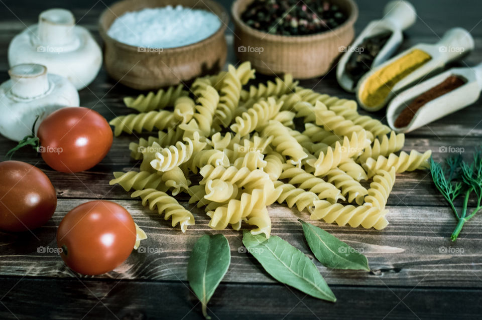 Raw pasta with ingredients and wooden accessories