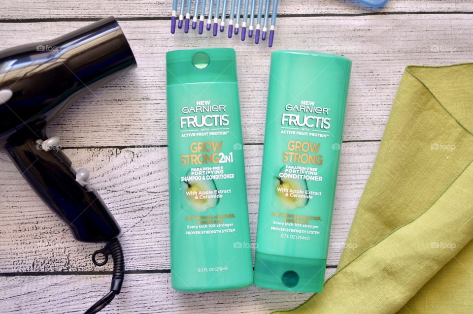 Garnier shampoo and conditioner only white rustic background with a comb in a hair dryer