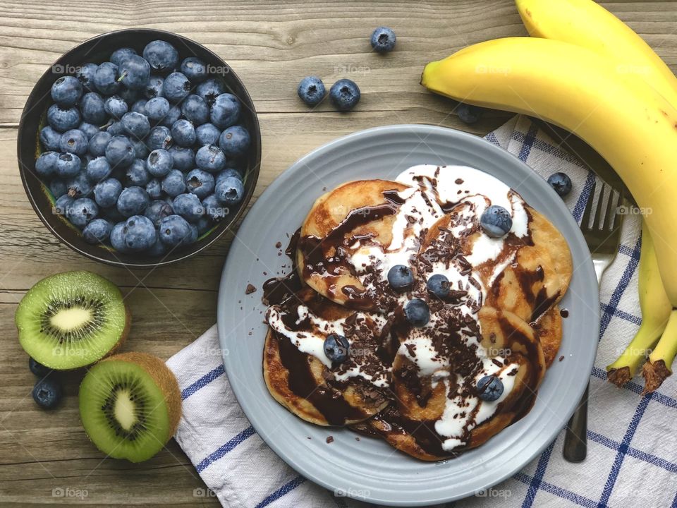 Pancakes with chocolate and fresh fruits - bananas, blueberries, kiwi