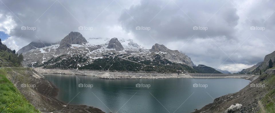Marmolada mount in summer time under a cloudy sky with the Fedaia lake , Dolomites of Italy