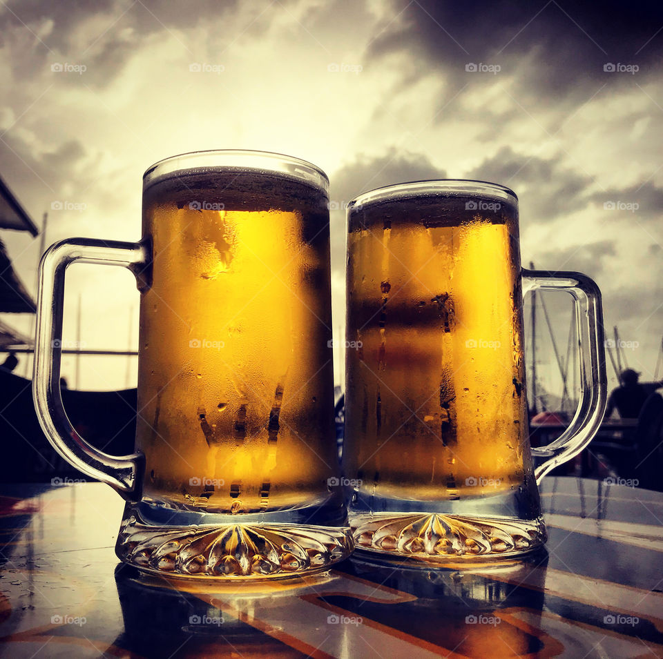 two glass mugs with cold yellow beer