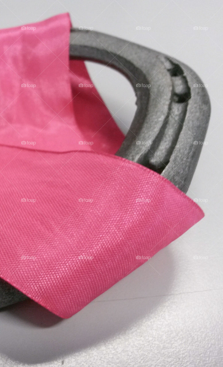 close up of detail of horseshoe with pink silk ribbonb