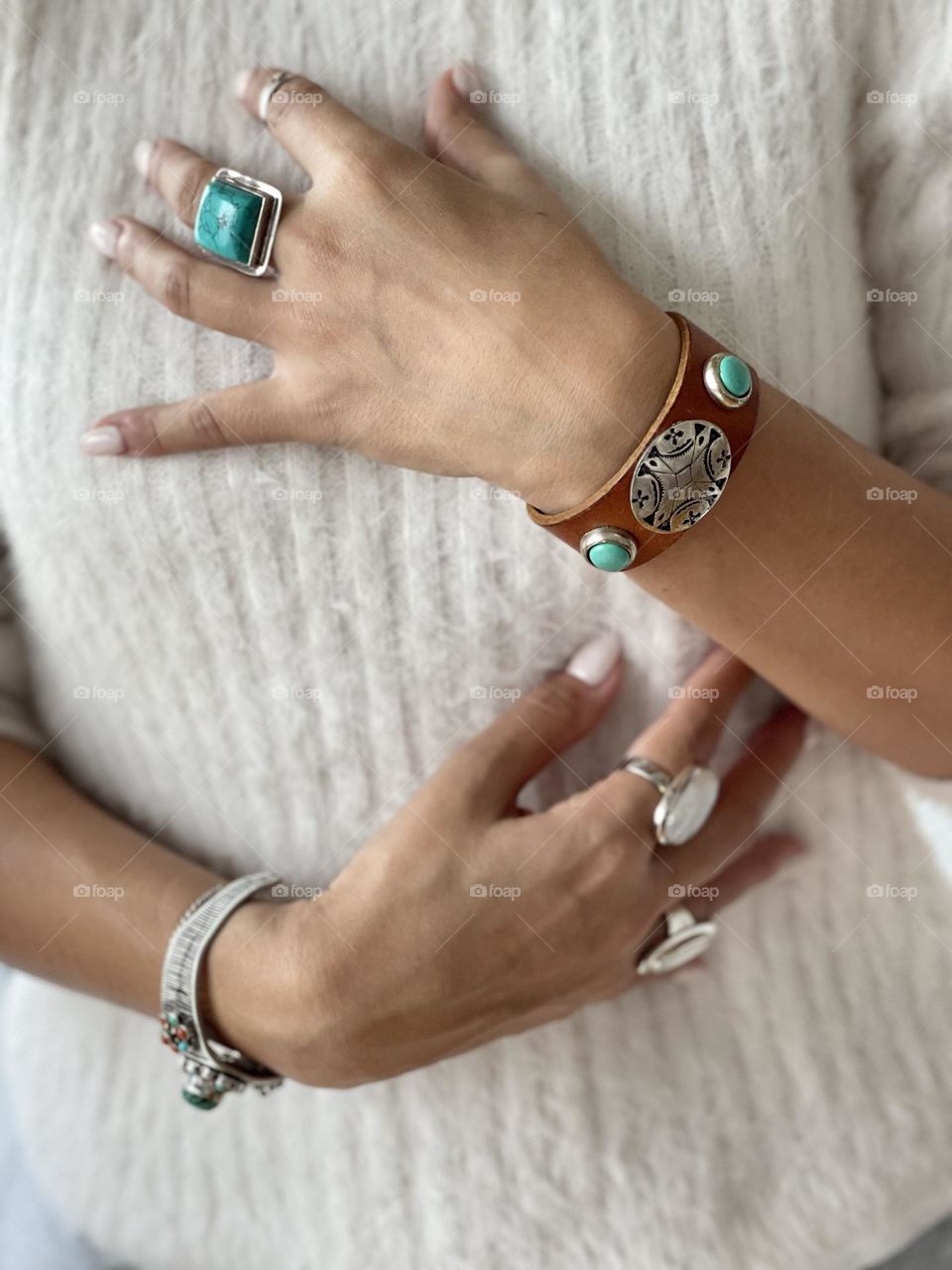 Woman’s hands wearing silver rings with semi precious stones and arms wearing silver bracelets