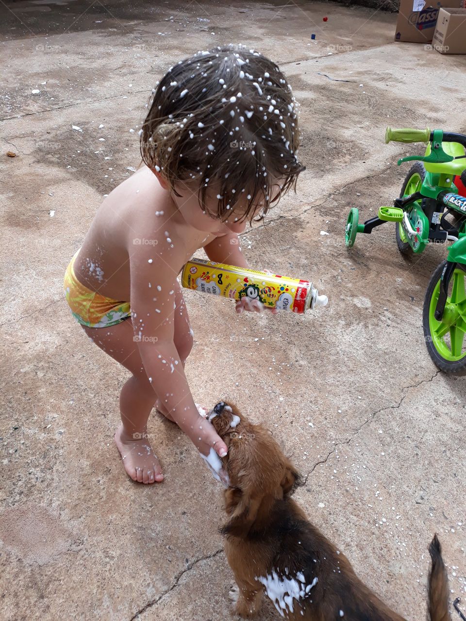 child playing with carnival foam with the little dog