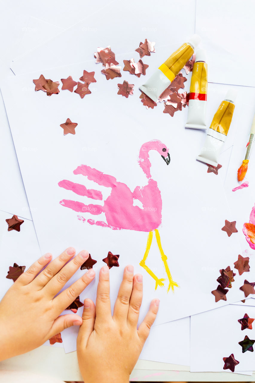 Hobby time. Child hands painting pink flamingo 