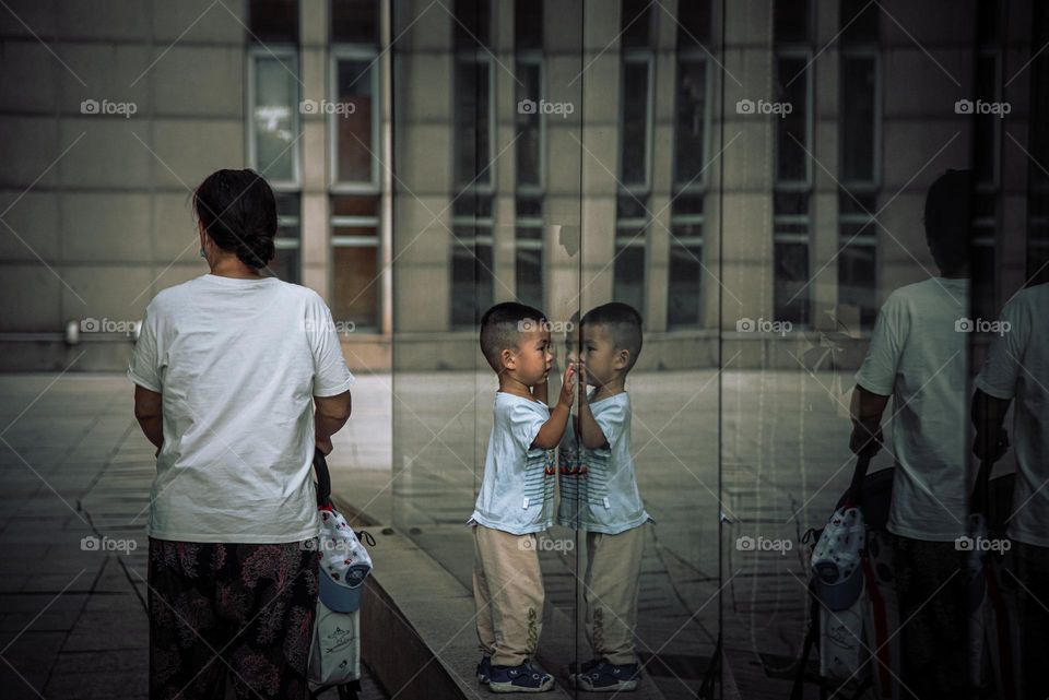 A boy is seeing himself through a glass