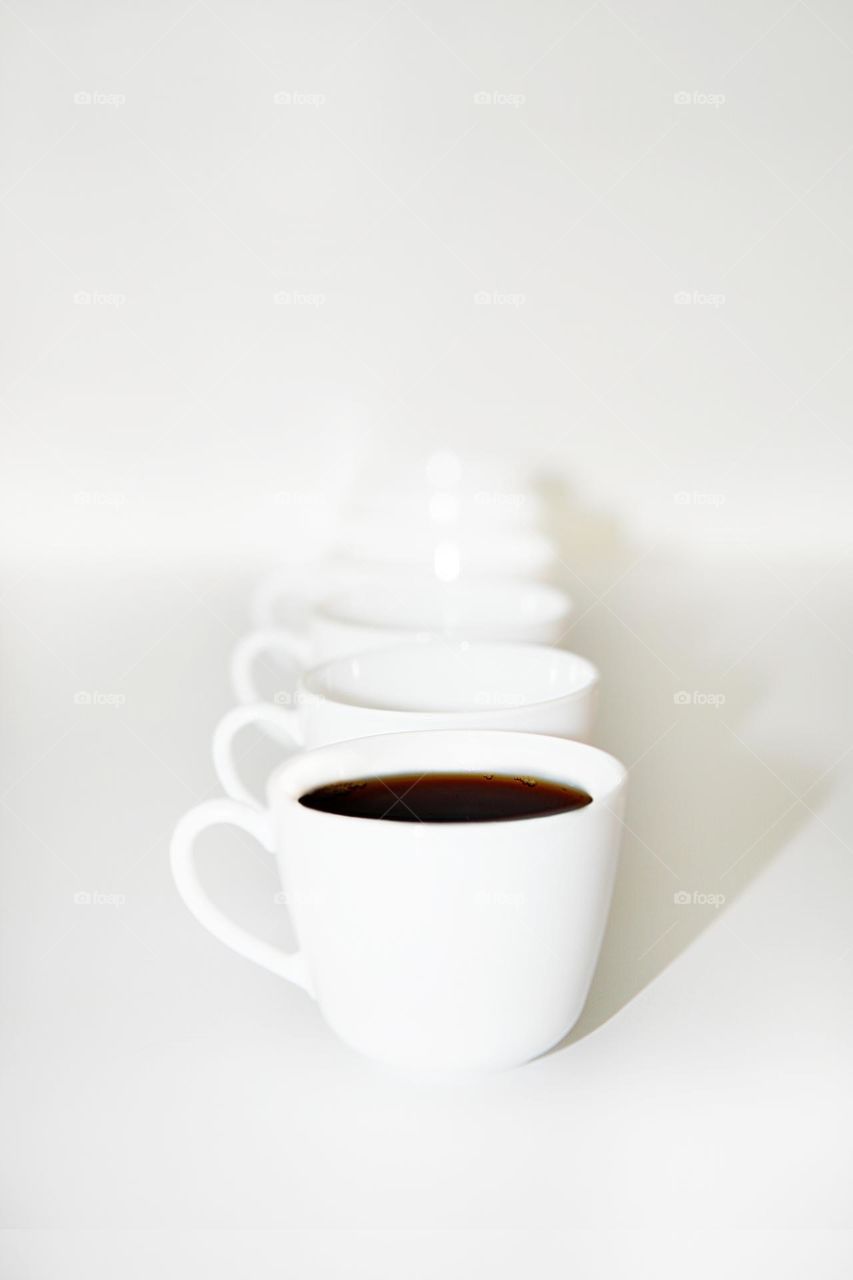 Row of white ceramic coffee cups on white background. Minimalism
