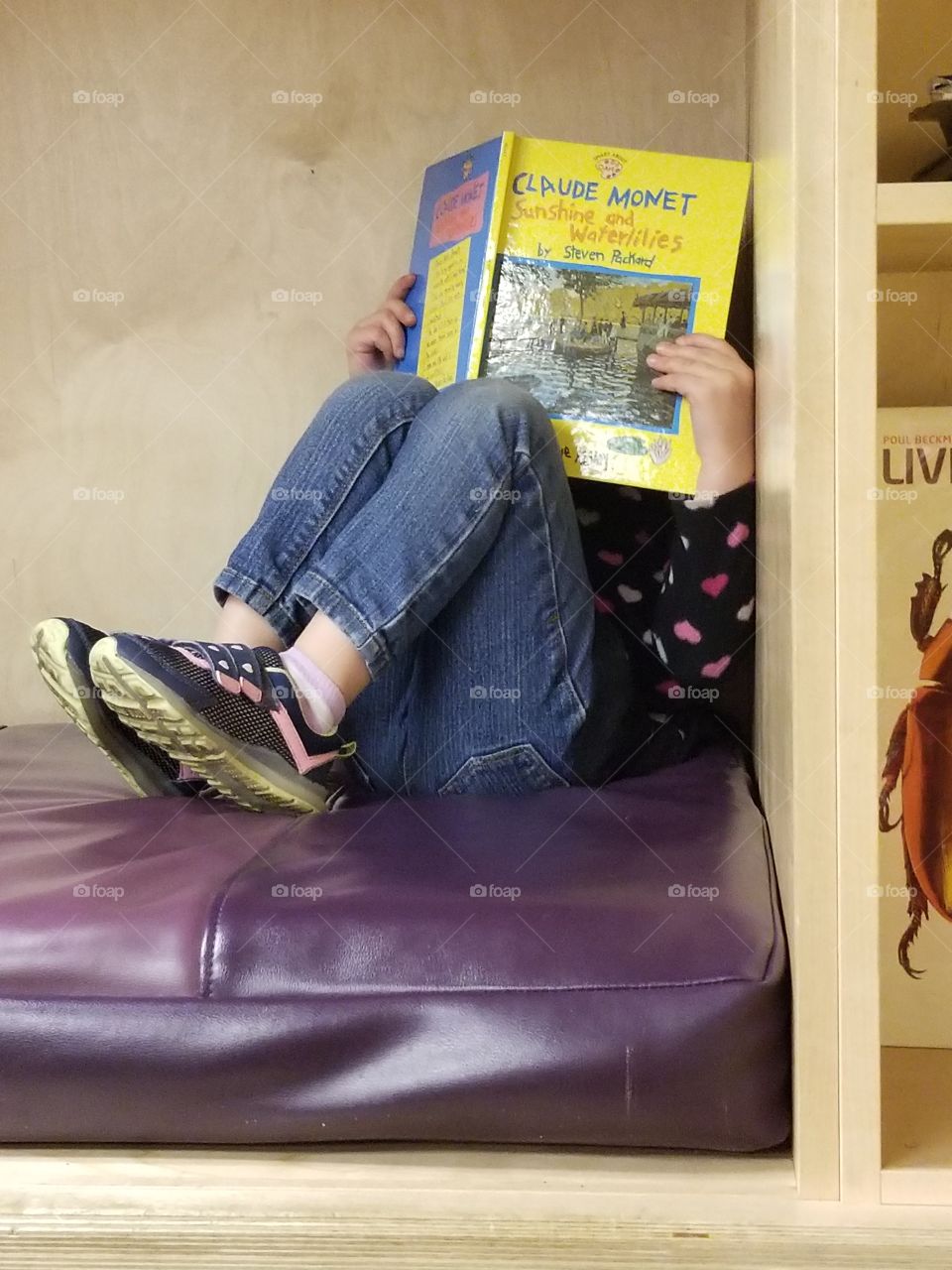 child hiding behind book