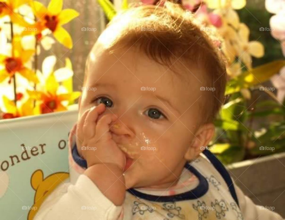 content 6 month old baby suckling on her thumb while in highchair