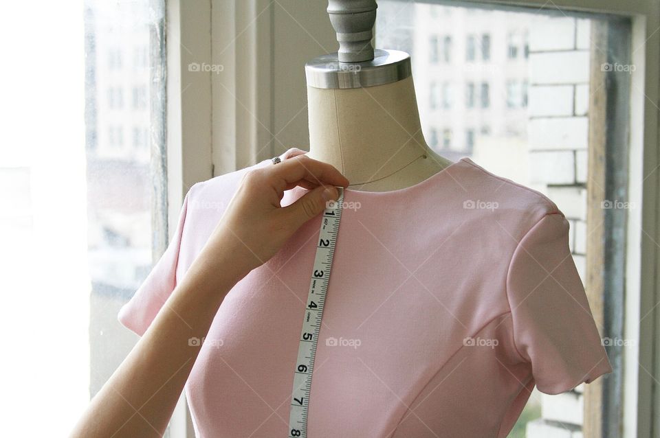 Fashion designer measuring pink dress