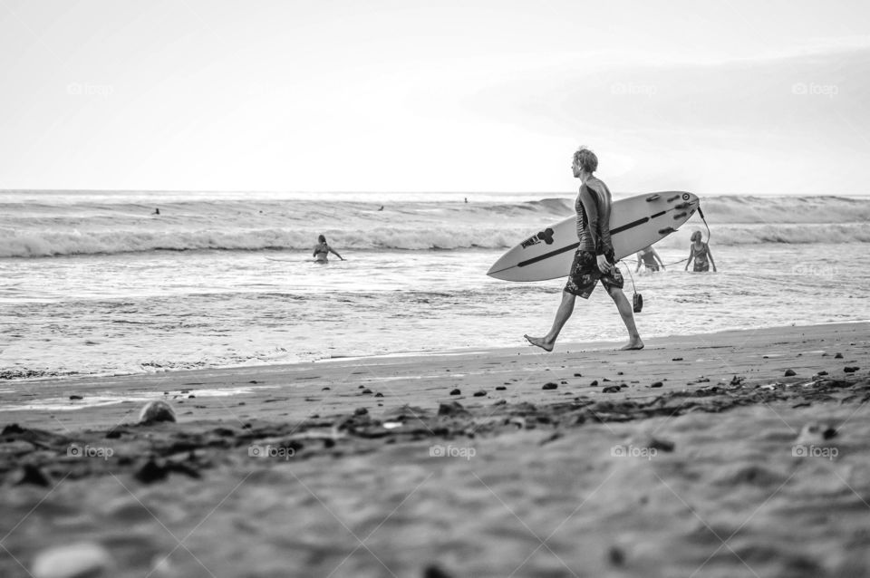 Surfer boy walking towards the sea with a surfboard