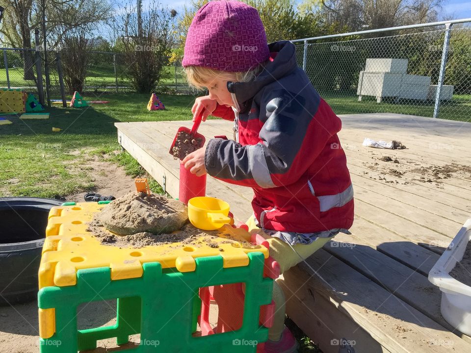 Little girl age of three playing in the sandbox at kindergarden in Malmö Sweden.