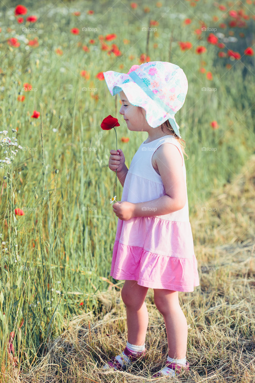 Lovely little girl in the field of wild flowers. Cute girl picking the spring flowers for her mom for Mother's Day in the meadow. Girl holding bouquet of flowers. Spending time close to nature