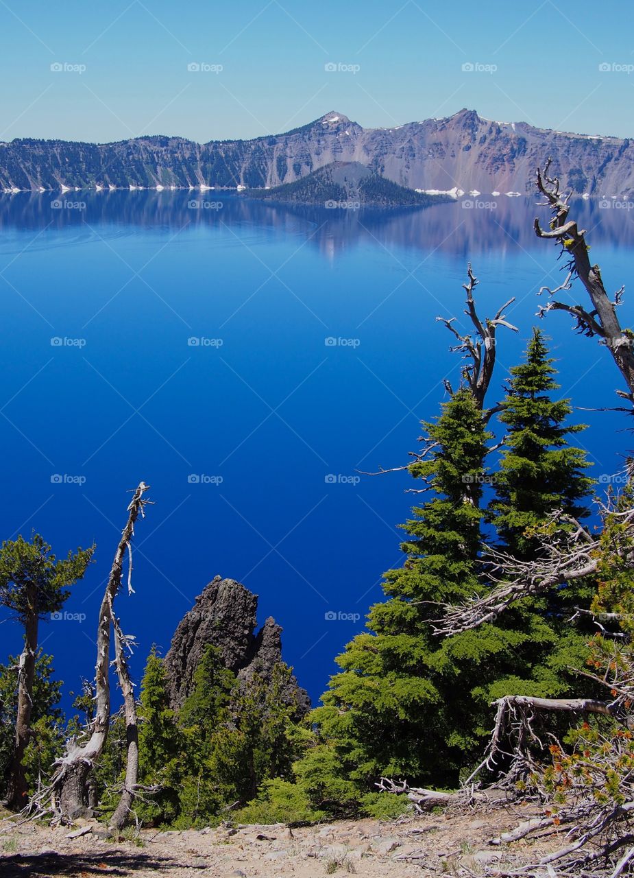 Wizard Island reflecting in the rich blue waters of Crater Lake in the forests of Southern Oregon on a sunny summer morning. 