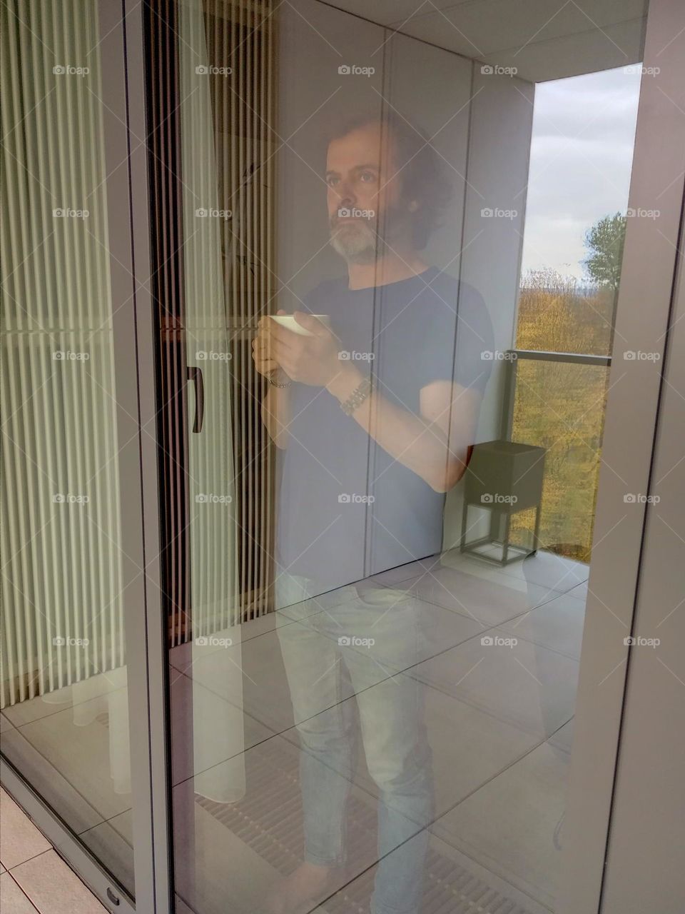 man looking out of Window With Cup in hands