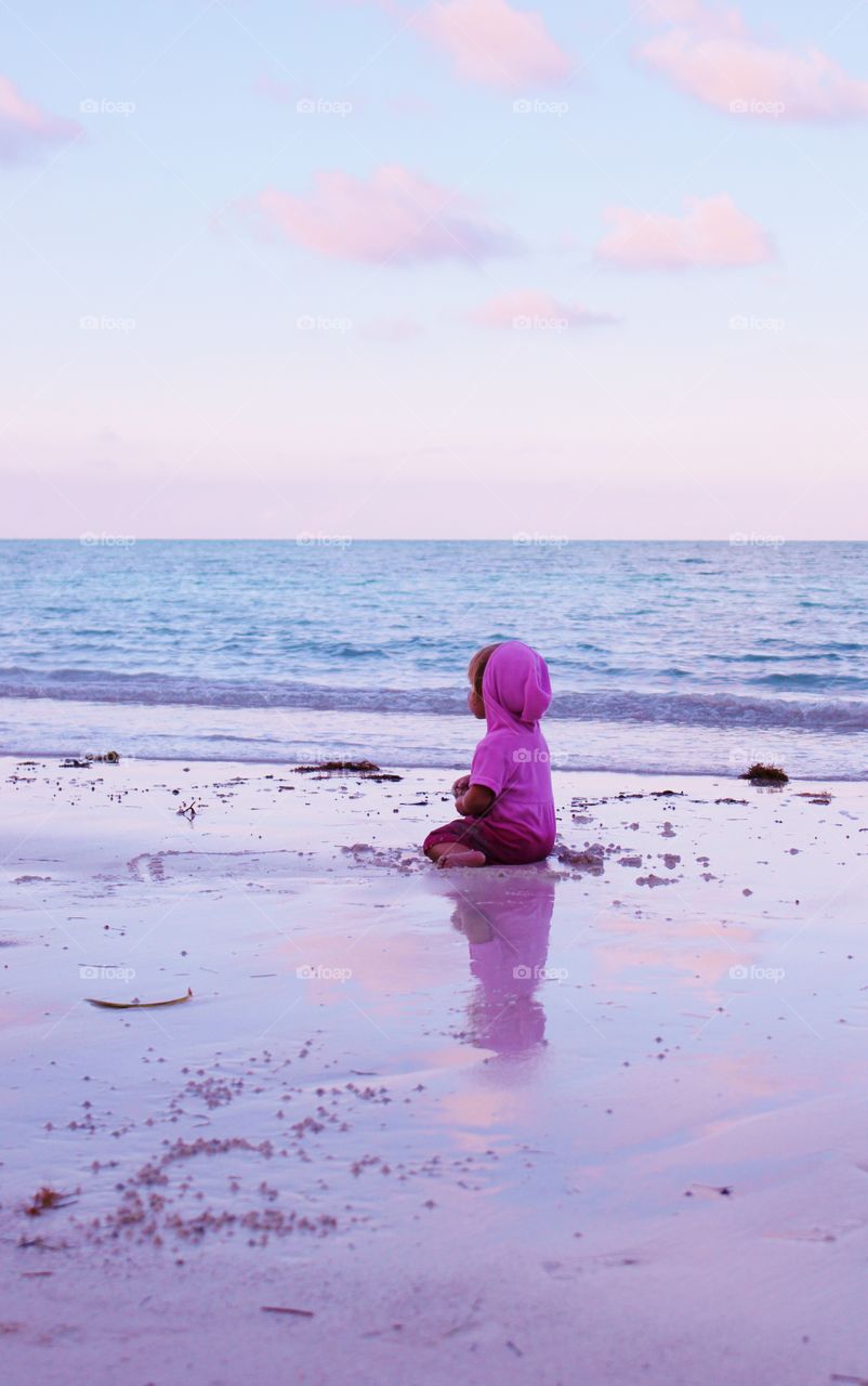 little girl admiring the pastel pink sunset at the beach