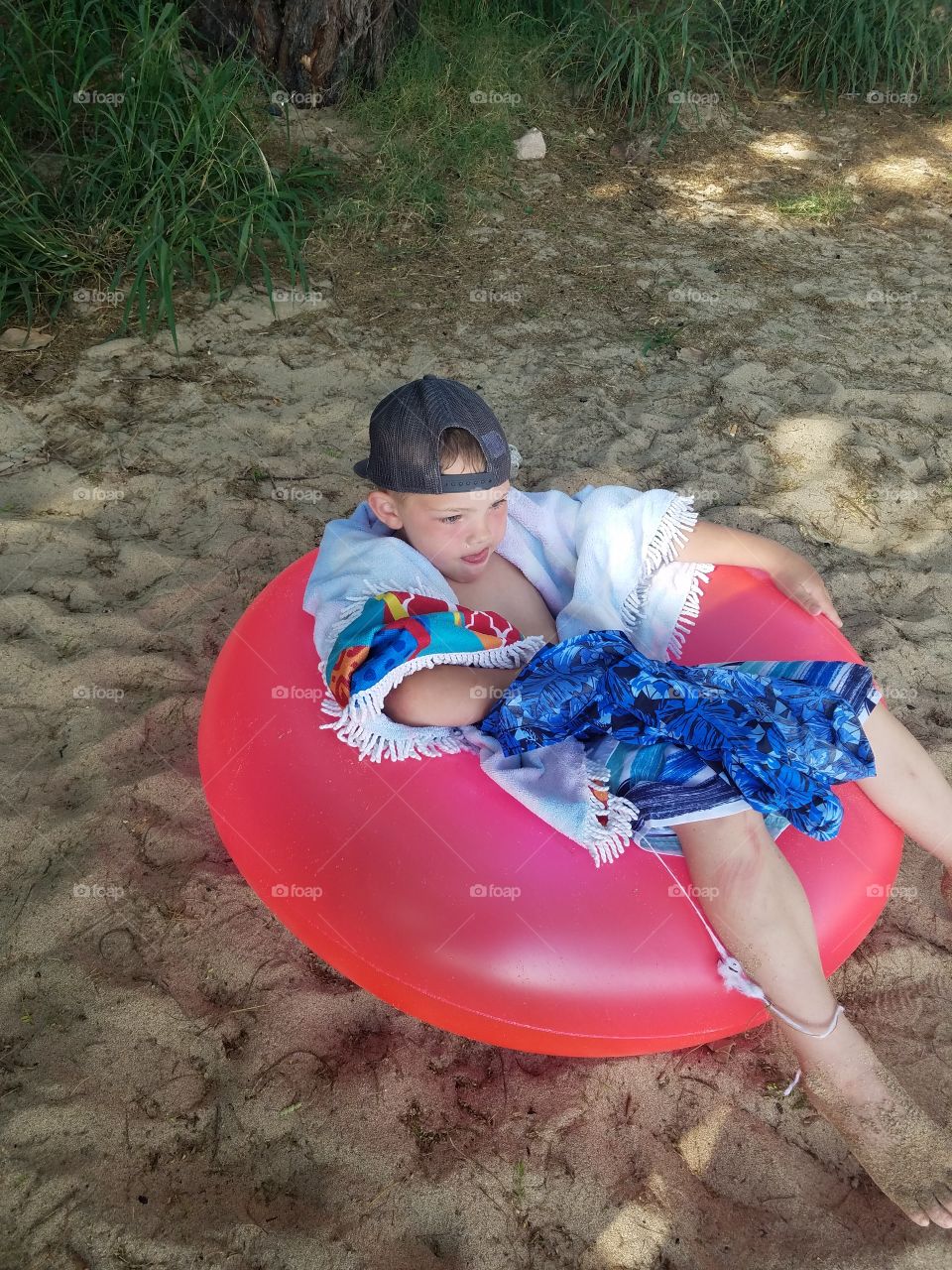 Boy lounges in a tube on the beach