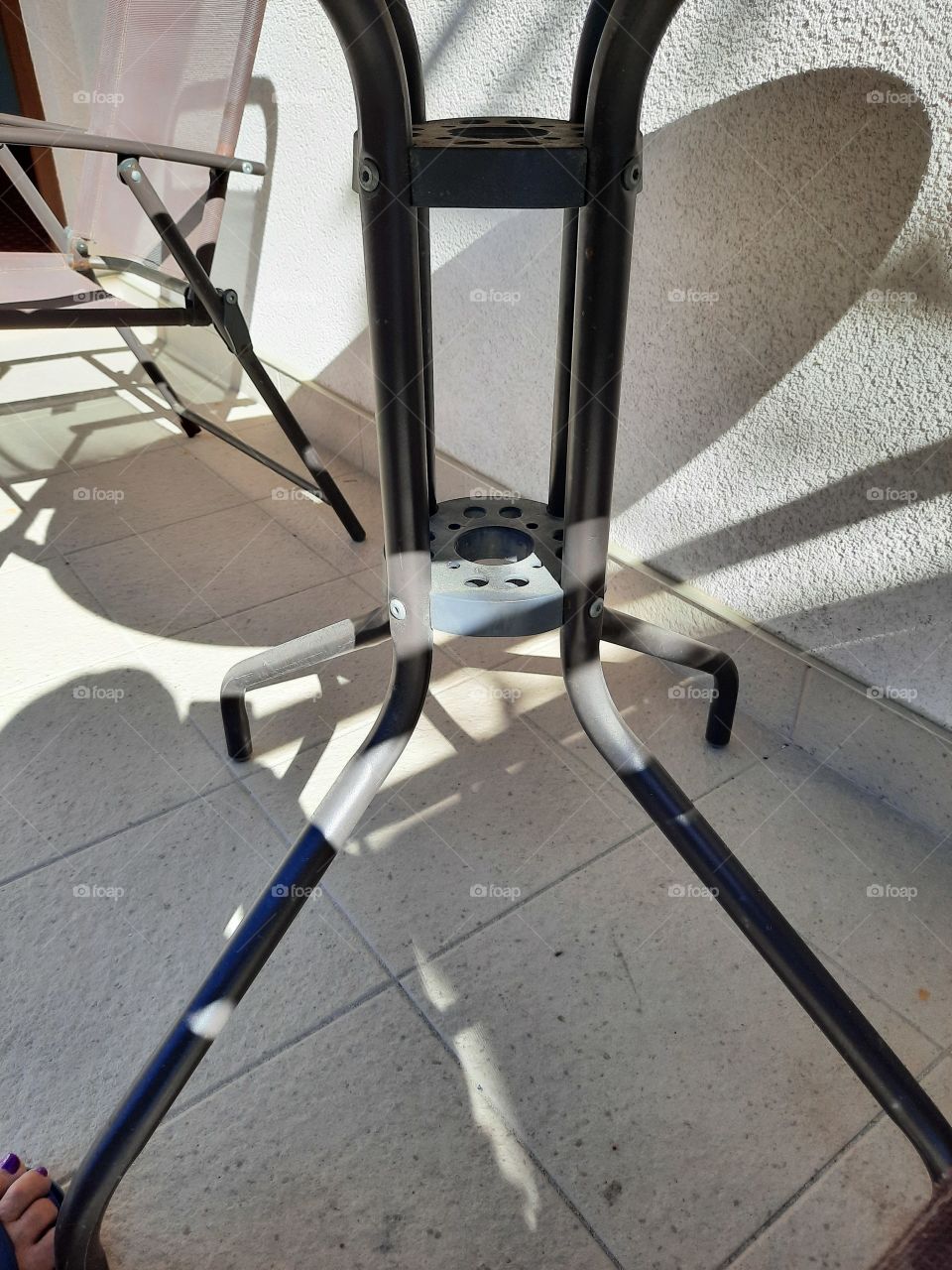 elementami of metal table and chair on a sunny terrace