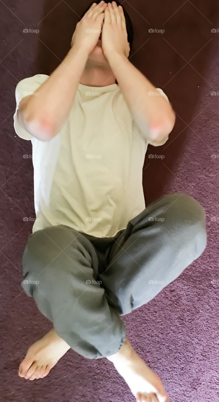 Man youth teen boy lying on floor carpet  legs folded hands over eyes